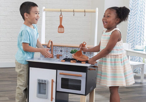 photo of two children playing with a Kid Kraft toy kitchen set