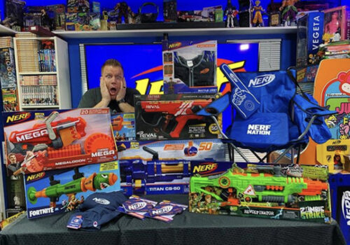 photo of a man gasping with two hands on his face behind a table full of nerf merchandise